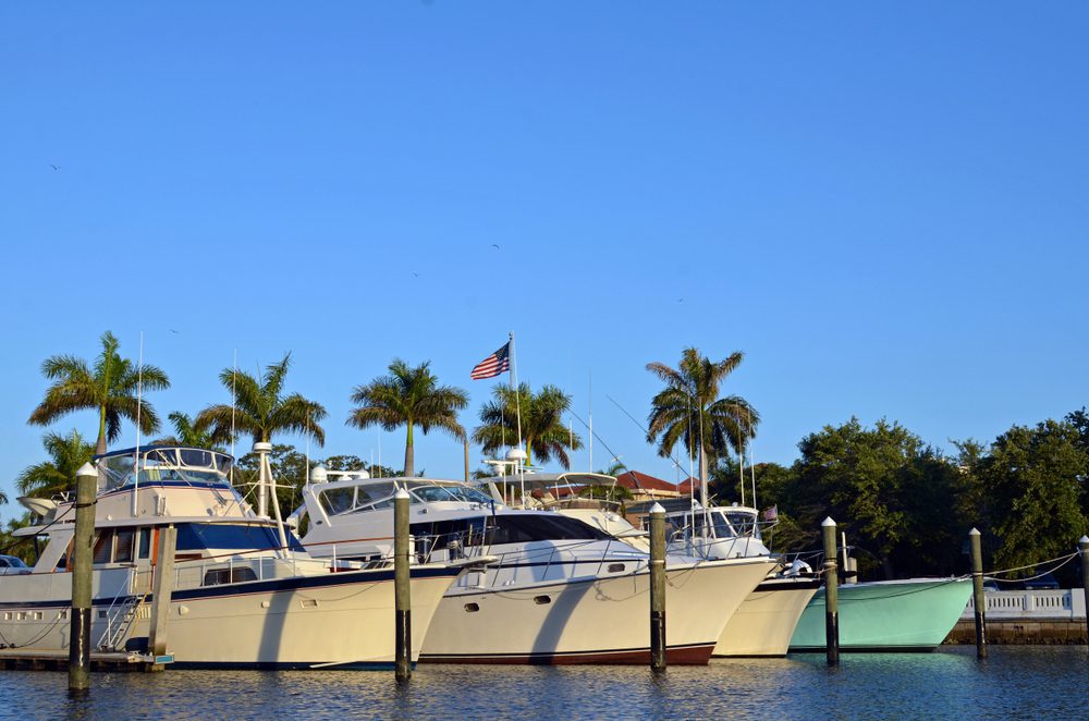 Three large powerboats docked in a marina in a tropical air location